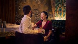 A well-dressed couple enjoys drinks at a marble bar