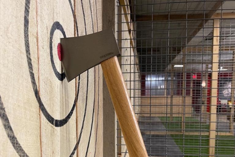 An axe embedded into the bullseye of a wooden target