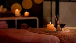 Photo of a spa tray with candles and fragrance diffuser sticks on a spa bed