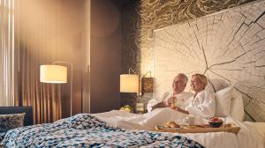 A couple in a hotel room bed with room service on a tray