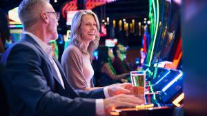 Two adults laugh while playing slot machines