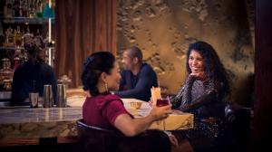 Two women enjoying drinks and conversing at a nightclub bar