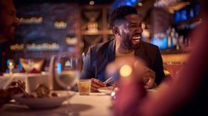 Gentleman laughing at dinner with friends in an intimate setting