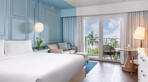A clean hotel room decorated in white and blue with a balcony