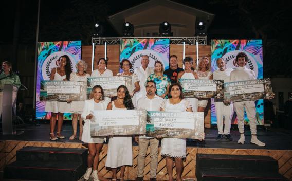 Six people holding large $10,000 checks on stage