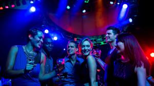 Young adults dancing and enjoying cocktails in a colorful club environment
