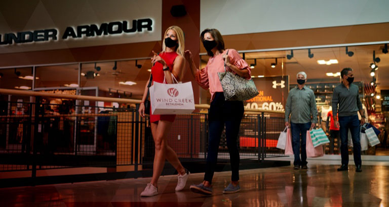 two women with masks holding shopping bags