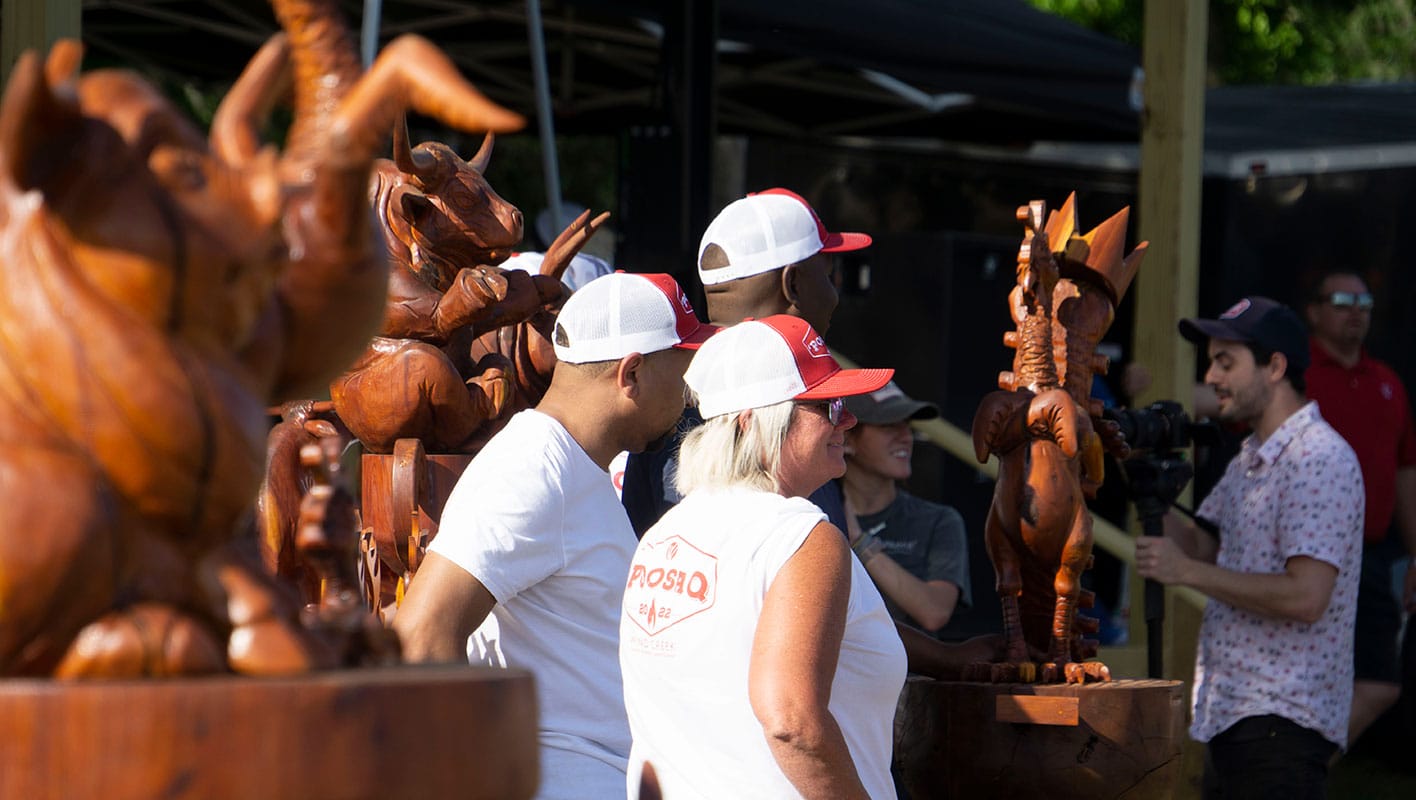 Several 'Poosa Q staff members standing among the hand-carved wooden trophies for the competition winners.