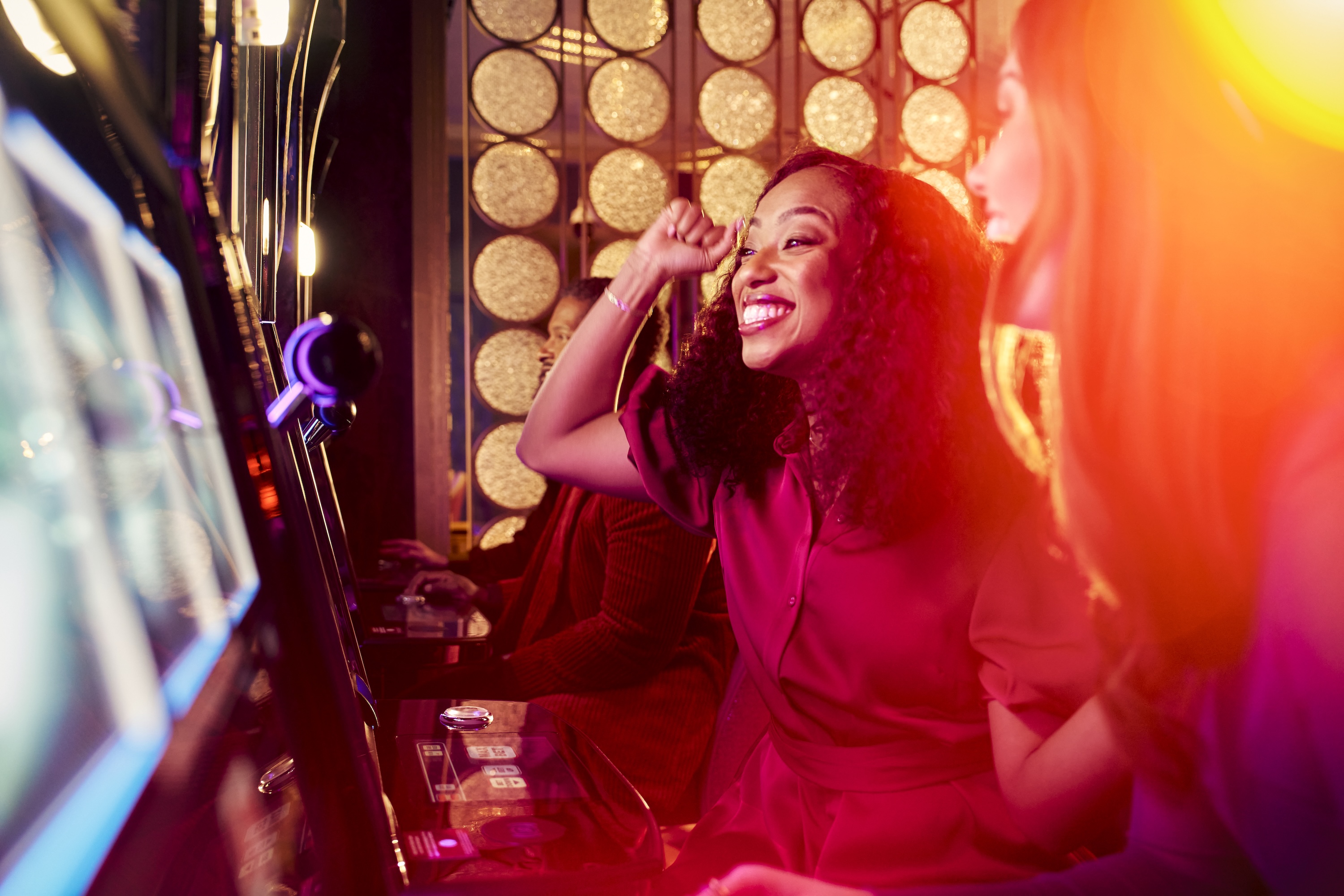 Women smiling in front of a slot machine.