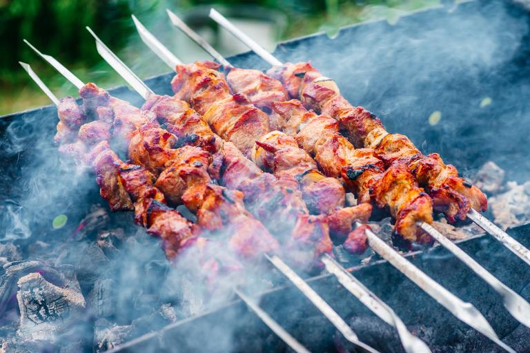 Skewers of meat suspended over a smoking bed of coals