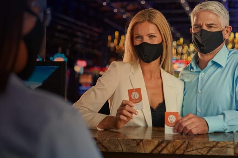 A man and a woman wearing masks check in to a Wind Creek hotel