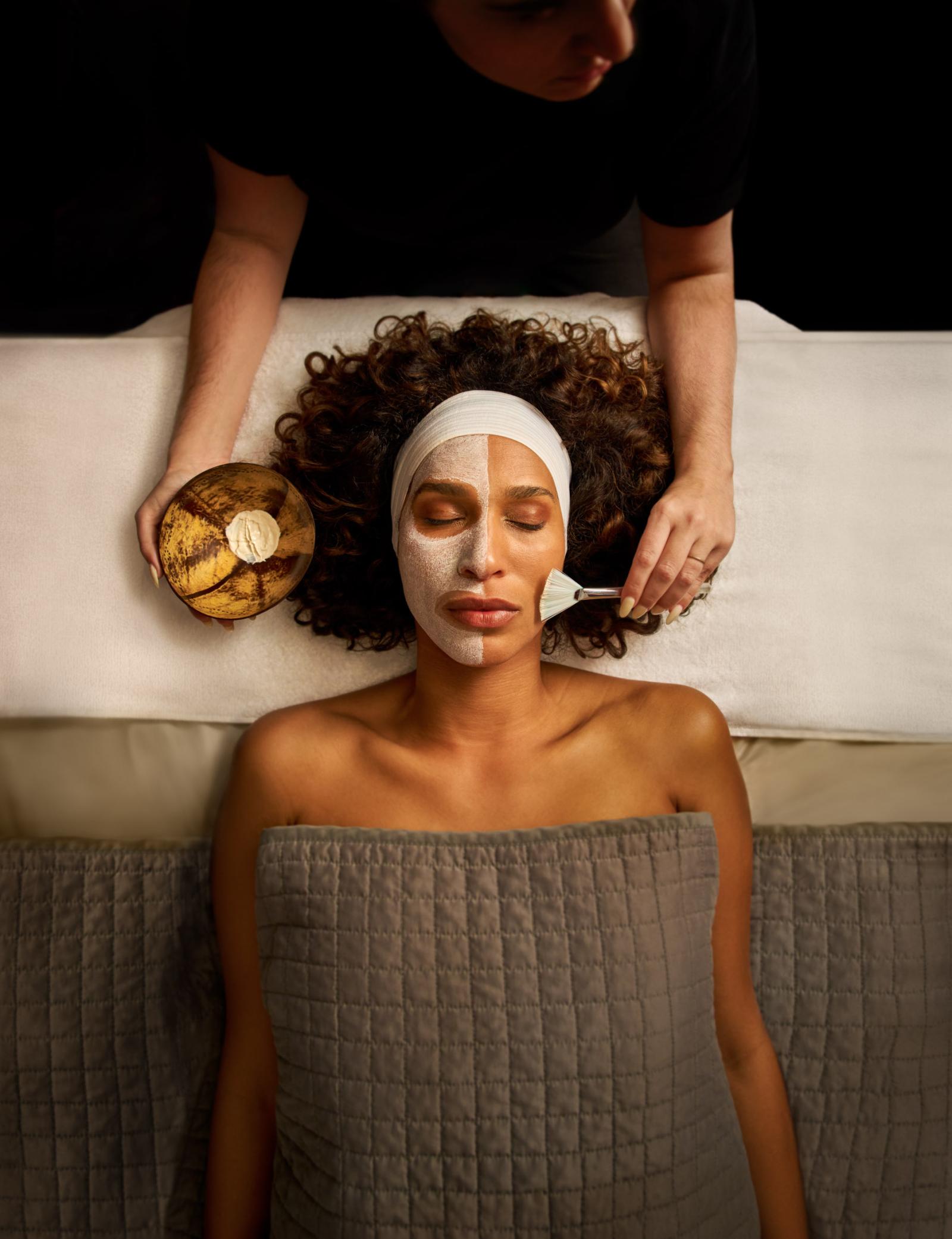 Woman relaxing while having a face mask painted on