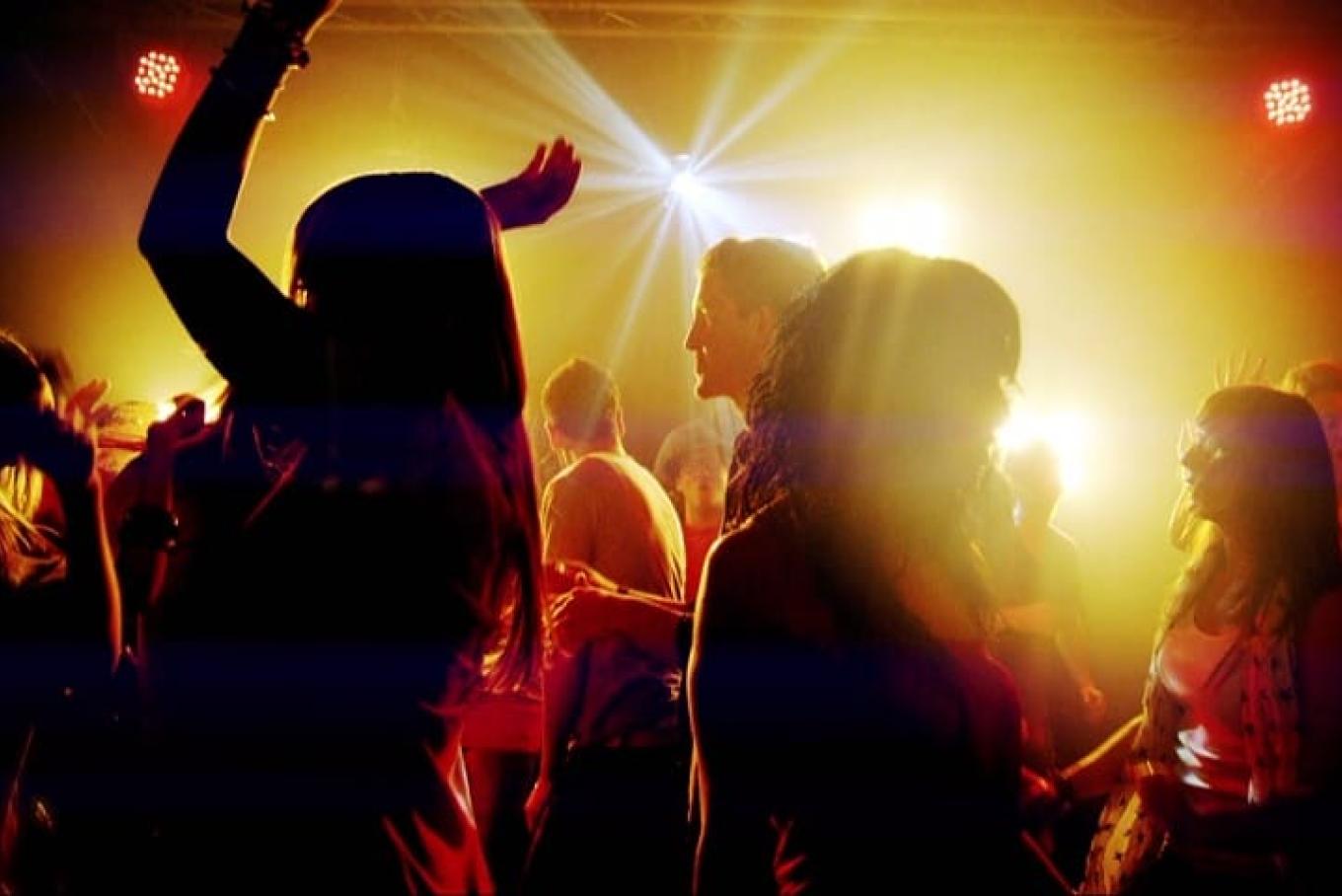 Adults dancing in a club under spotlights