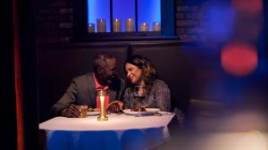 A couple sits close together in a dimly lit booth